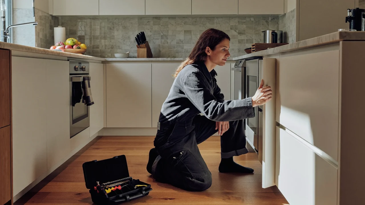 Tecnico in una cucina milanese mentre ispeziona un apparecchio da incasso aperto